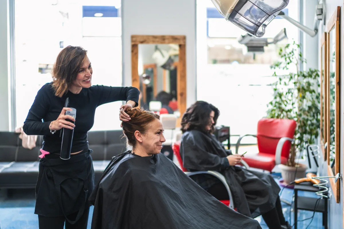 Cosmetologist styling a client's hair in a salon